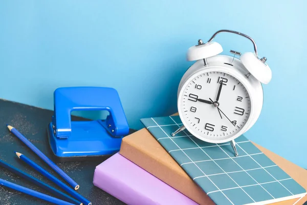 Conjunto de útiles escolares y reloj en la mesa contra el fondo de color —  Fotos de Stock