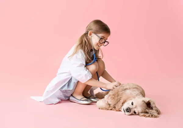 Cute little veterinarian with dog on color background — Stock Photo, Image