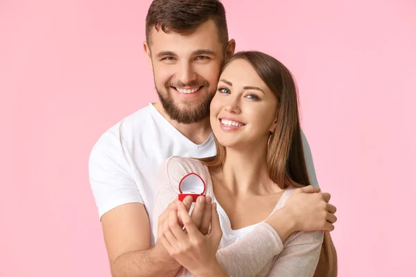 Junger Mann macht seiner Geliebten auf farbigem Hintergrund einen Heiratsantrag — Stockfoto