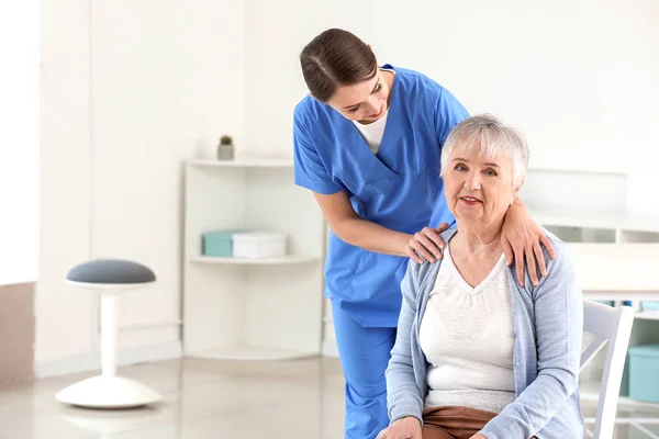 Médica com mulher idosa que sofre de síndrome de Parkinson na clínica — Fotografia de Stock