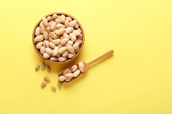 Skål med välsmakande pistagenötter på färgbakgrund — Stockfoto