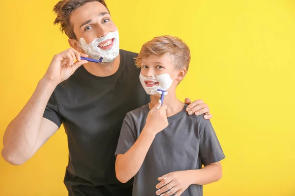 Vader en zijn zoontje scheren zich tegen kleur achtergrond — Stockfoto