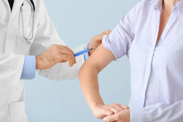 Doctor vaccinating young woman on light background, closeup — Stock Photo, Image