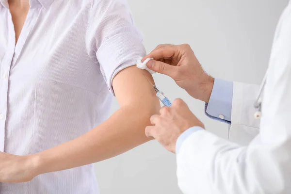 Médico vacinar jovem mulher no fundo claro, close-up — Fotografia de Stock