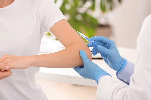 Läkare vaccinerar ung kvinna på kliniken, närbild — Stockfoto