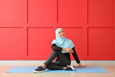 Spor yapan Müslüman kadın duvar kenarında yoga yapıyor.