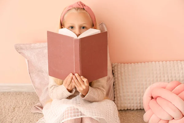 Μικρό κορίτσι ανάγνωση βιβλίο κοντά στον τοίχο χρώμα — Φωτογραφία Αρχείου