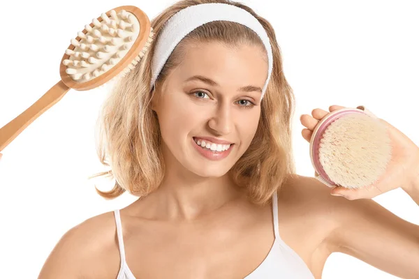 Beautiful young woman with massage brushes on white background — Stock Photo, Image