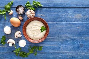 Mantar soslu kase ve masada malzemeler.