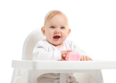 Süt şişeli bebek beyaz arka planda yüksek sandalyede oturuyor.