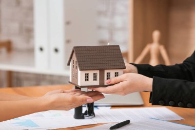 Ofisinde ev modeli olan emlakçı ve müşteri.