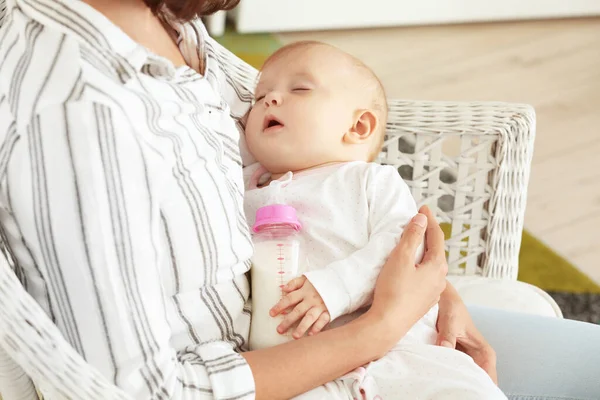 Мама со спящим ребенком и бутылкой молока дома — стоковое фото