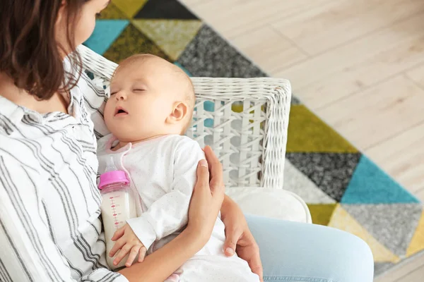 Madre con bebé dormido y biberón de leche en casa —  Fotos de Stock
