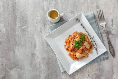 Plate with tasty rice and chicken on grey background