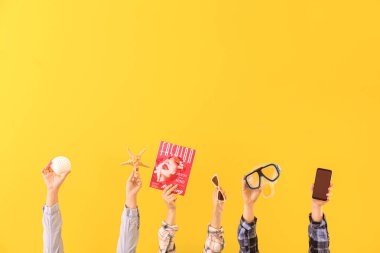 Many hands with travel items on color background