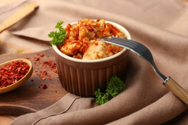Bowl with tasty rice, chicken and spices on table