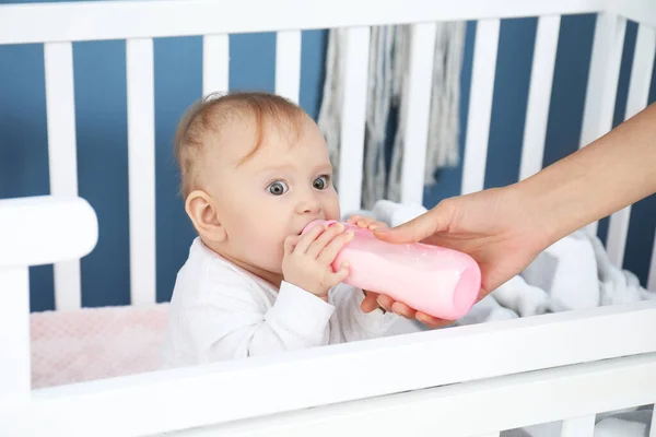 Мать кормит ребенка молоком из бутылки в спальне — стоковое фото