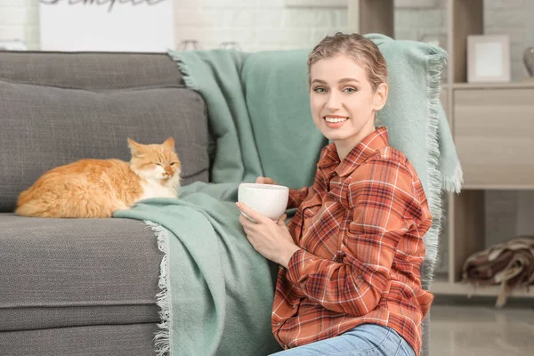 Bella giovane donna con gatto carino bere il tè a casa — Foto Stock