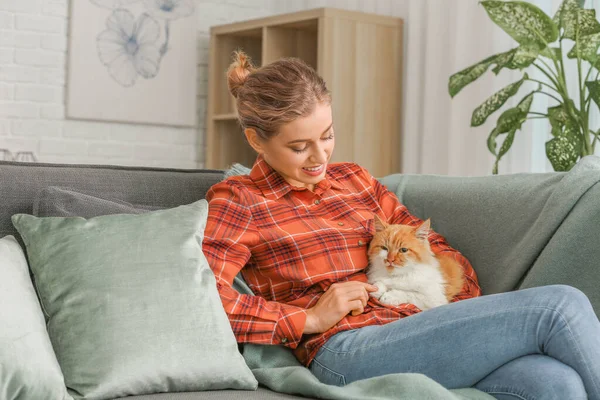 Bella giovane donna con gatto carino seduto sul divano a casa — Foto Stock