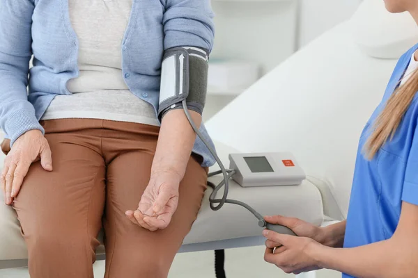 Médica que mede a pressão arterial de mulheres idosas que sofrem de síndrome de Parkinson na clínica — Fotografia de Stock