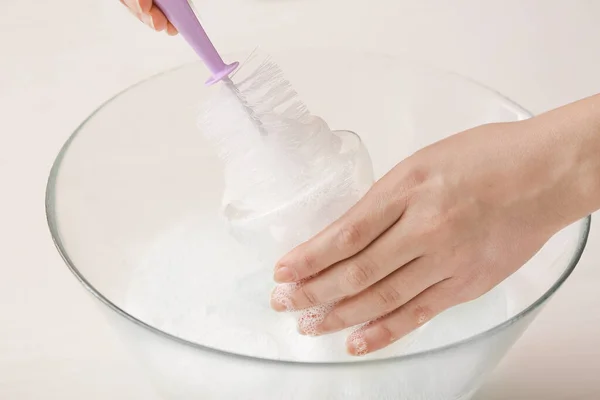 Woman cleaning baby bottle at home, closeup — Stock Photo, Image