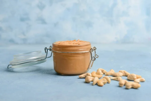 Glas Cashewbutter auf farbigem Hintergrund — Stockfoto