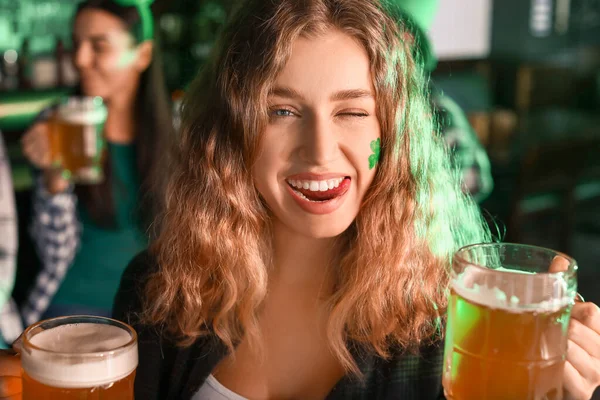 Молодая женщина с пивом празднует День Святого Патрика в пабе — стоковое фото