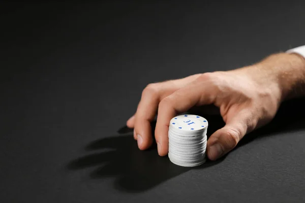 Männliche Hand mit Chips für Glücksspiele auf dunklem Hintergrund — Stockfoto