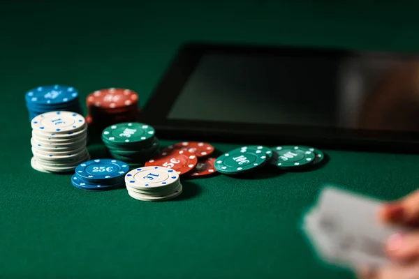 Chips for gambling games with tablet computer on color background — Stock Photo, Image