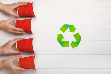 Hands with used cups on white wooden background. Concept of recycling