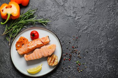 Lezzetli pişmiş somon ve koyu arkaplanda sebze tabağı