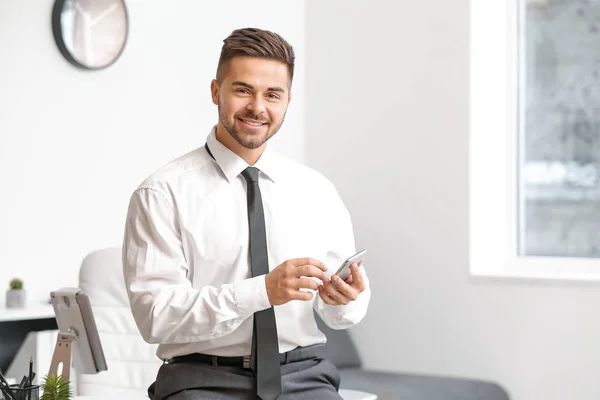 Young businessman with mobile phone in office — Stock Photo, Image