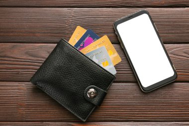 Ahşap arka planda cüzdanı ve cep telefonu olan kredi kartları. Çevrimiçi bankacılık kavramı