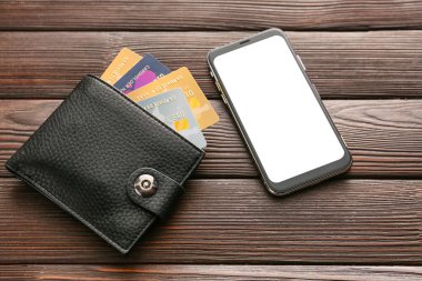 Ahşap arka planda cüzdanı ve cep telefonu olan kredi kartları. Çevrimiçi bankacılık kavramı