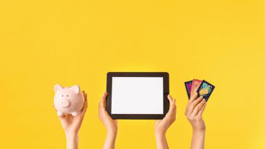 Kumbarası olan kadın eller, kredi kartları ve renkli tablet bilgisayarlar. Çevrimiçi bankacılık kavramı