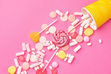 Renkli arkaplanda lezzetli şekerler olan fincan