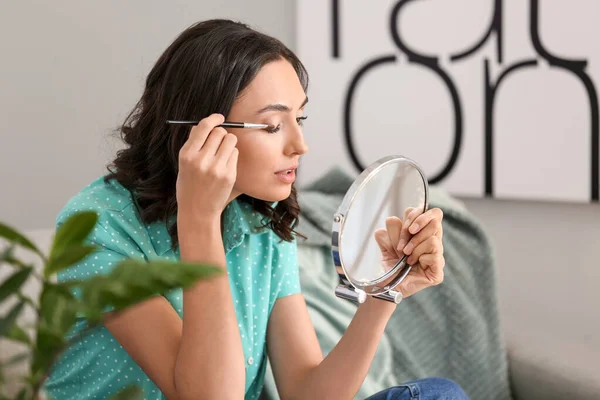 Smuk ung kvinde, der anvender makeup derhjemme - Stock-foto