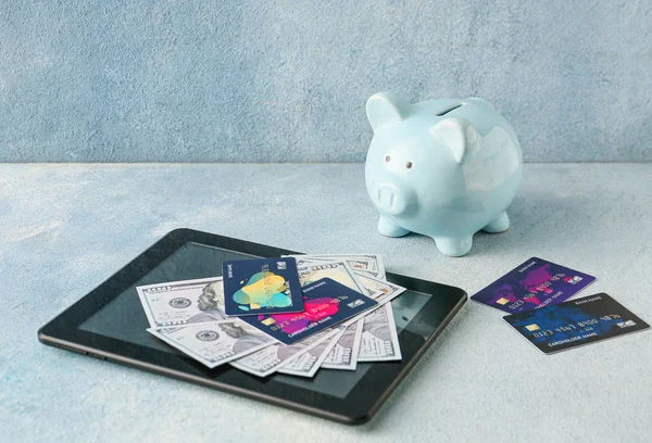 Tablet z kartami kredytowymi, pieniędzmi i skarbonką na kolorowym tle. Pojęcie bankowości internetowej — Zdjęcie stockowe