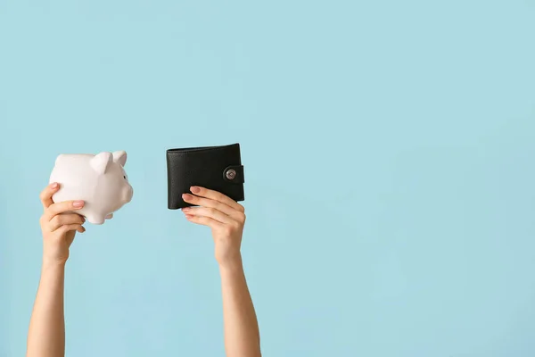 Female hands with piggy bank and wallet on color background — Stock Photo, Image