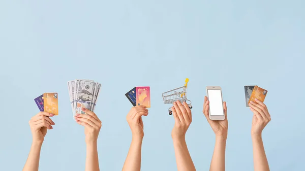 Жіночі руки з грошима, кредитними картками, кошиком для покупок та мобільним телефоном на кольоровому фоні. Концепція онлайн банкінгу — стокове фото