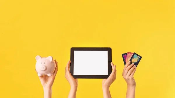 Female hands with piggy bank, credit cards and tablet computer on color background. Concept of online banking — Stock Photo, Image