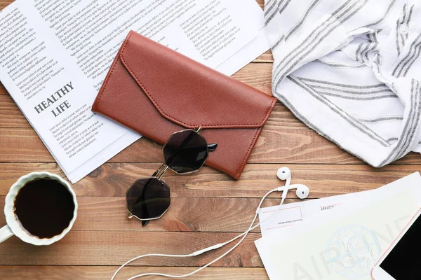 Πορτοφόλι με ρούχα, καφέ, εφημερίδα και γυαλιά ηλίου σε ξύλινο φόντο — Φωτογραφία Αρχείου