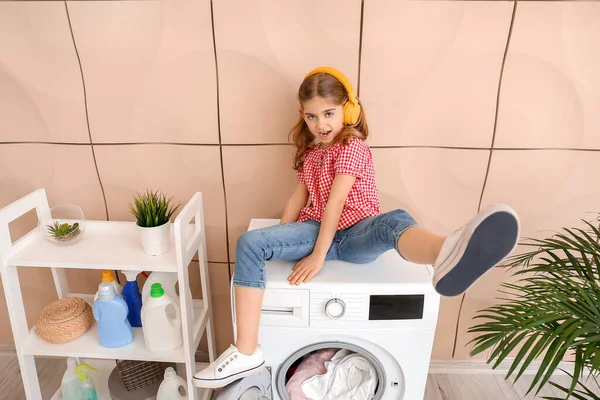 Pequeña ama de casa escuchando música en la lavandería — Foto de Stock