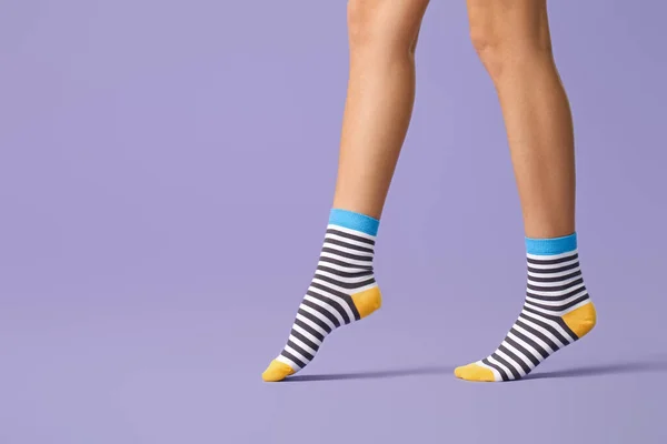 穿着条纹袜的年轻女子的腿，背景为彩色 — 图库照片
