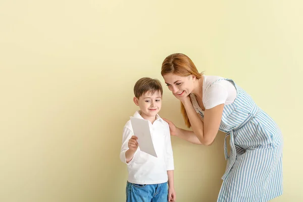 Glad liten pojke hälsar sin mor på färg bakgrund — Stockfoto