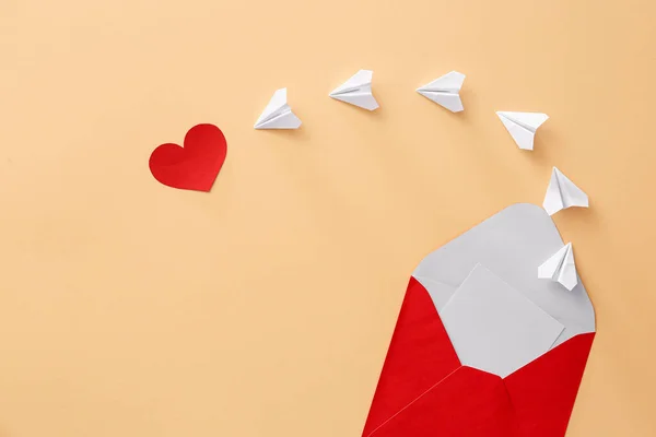 Komposition mit Umschlag, Papierflugzeugen und Herz auf farbigem Hintergrund — Stockfoto
