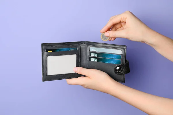 手握皮夹、信用卡和彩色背景硬币的女性 — 图库照片