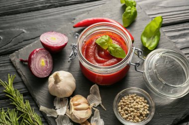 Domates soslu kavanoz ve malzemeler masada.