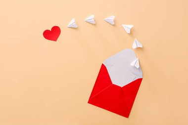 Zarflı kompozisyon, kağıt uçaklar ve renk arkaplanlı kalp.