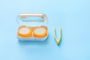 Renk arkaplanında kontak lens ve cımbızla konteyner